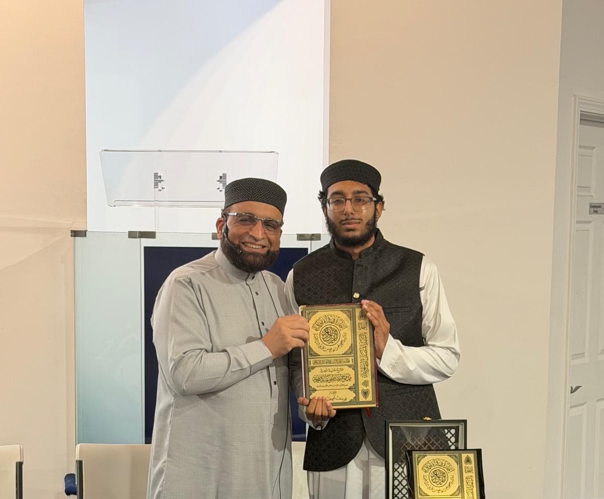 Dr. Shaykh Mamdouh conferring a certificate on a graduate in a black vest.